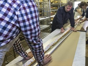 SASKATOON, SASK.; NOVEMBER  24, 2015 -   Randy Shaw, Carmen Dyck and Tom Carey and Anna Weinard help with this cooked 19' long long john moving it to some tables keeping it in the eavestrough it was cooked in at NestorÕs Bakery where students of the Community LearnerÕs High School are attempting to make the worldÕs longest long john donut measuring in at over 19' 1 1/2 "  November 24, 2015. Keith Jorgensen with helpers Randy Shaw, Anna Weird, Janet Neu, Tom Carey and Carmen Dyck all participated.  (GORD WALDNER/Saskatoon StarPhoenix)