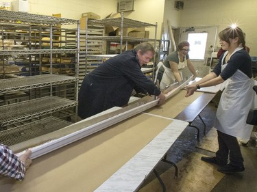 Randy Shaw, Carmen Dyck, Tom Carey and Anna Weinard help with this cooked 19-foot long john, moving it to some tables keeping it in the eavestrough it was cooked in, at Nestor's Bakery where students of the Community Learner's High School are attempting to make the world's longest long john donut, November 24, 2015. It measured in at just over 19' 1 1/2" long.