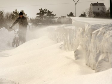 A cyclist chooses to walk through building drifts on 108th Street East caused by drifting snow, March 2, 2015.