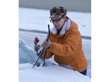 Saskatoon was coated in its first snowfall of the year following an overnight rain which made roads slippery for motorists and pedestrians, November 18, 2015. Willow Bell cleans her wipers before driving on the east side.