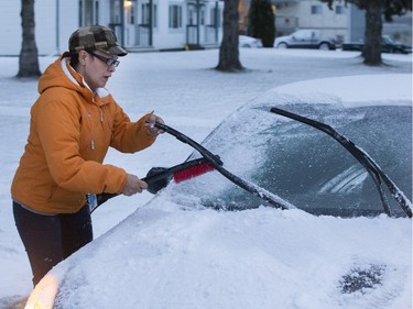 Saskatoon was coated in its first snowfall of the year following an overnight rain which made roads slippery for motorists and pedestrians, November 18, 2015. Willow Bell cleans her wipers before driving on the east side.