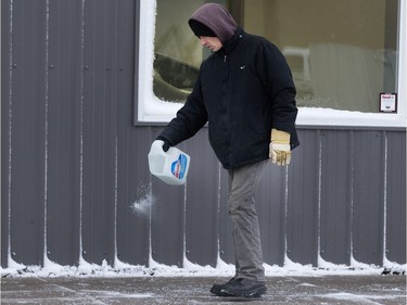 Saskatoon was coated in its first snowfall of the year following an overnight rain which made roads slippery for motorists and pedestrians, November 18, 2015. Brian Maser puts down some salt in front of a 21st Street West business for pedestrians.