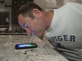 Simonar uses a stylus in his teeth to scroll his smartphone, Tuesday, November 24, 2015.