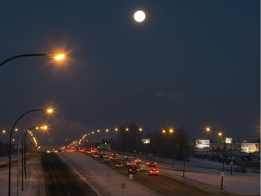 The moon sets over College Drive traffic, November 26, 2015.