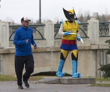A jogger on Spadina Crescent East passes the statue dedicated to former radio personality and avid runner Denny Carr,   November 4, 2015. It has become a local tradition for the statue to be decorated in seasonal attire, this time Wolverine for Halloween.