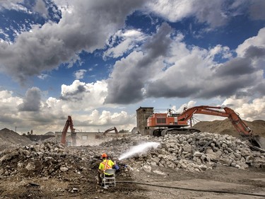 A Rakowski Excavation employee sits comfortably while using a hose to settle the dust the heavy equipment stirs up while moving the demolished P&H Elevator concrete, July 13, 2015.