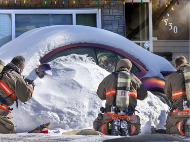 Firefighters stop to put on their oxygen masks before entering a smoke-filled home on First Avenue North, March 4, 2015.