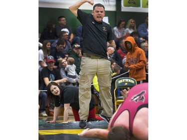 Two Marion Graham Falcons coaches, one flexing his muscles after watching one of his wrestlers win his match at the Saskatoon High School Wrestling Championships, March 6,  2015.