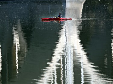 A kayaker drifts underneath the University Bridge surrounded by reflections of the bridge supports on a balmy October 16, 2015 in Saskatoon.