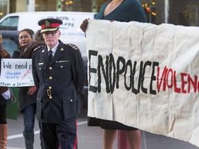 Saskatoon Police Chief Clive Weighill stands and listens to concerns of citizens protesting against his police force, Oct. 7, 2015 before a public consultation on policing took place inside TCU Place.