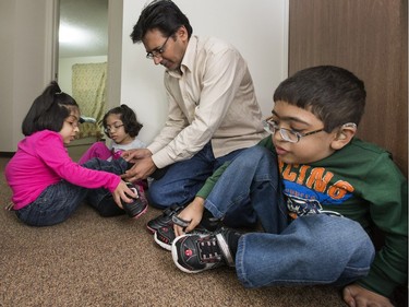 Father Muhammad Amir Akhter helps children (L-R) Khadija, Sara and Muhammad Abdullah with their shoes before heading off to school at River Heights, September 16, 2015.
