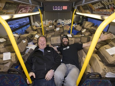 Rock 102 radio personalities Mark Loshack and Derek Watson amongst the pile of donated food on a city bus during the annual Stuff the Bus campaign for the Saskatoon Food Bank and Learning Centre at The Centre mall, December 10, 2015.