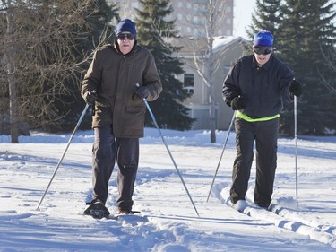 Earl Ripley, on snowshoes (L), and Glenn Kurmey, on skis, get in a workout in the snow in Lakewood Park, Dec. 1, 2015.