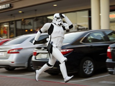 Taylor Wren, dressed as a Storm Trooper, races across a strip shopping center parking lot as he was running late to a group photo outside the Alamo Drafthouse cinema in Richardson, Texas, where Star Wars: The Force Awakens movie was showing, Thursday, Dec.17, 2015.