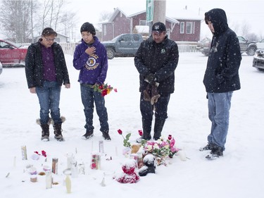 A family in La Loche pays their respects on January 23, 2016 to the victims of a Friday school shooting. The shooting left four people dead.