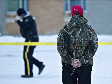 A man holds a rosary as police investigate the scene of a shooting at the community school in La Loche, January 23, 2016. The shooting took place on Friday, leaving four people dead.