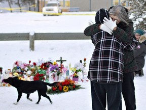 Residents console each other at the memorial near the La Loche Community School in La Loche, Jan. 24, 2016. A shooting Friday left four people dead.