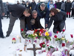 La Loche Mayor Kevin Janvier, left to right, Saskatchewan Premier Brad Wall, federal Public Safety Minister Ralph Goodale and MLA Georgina Jolibois lay flowers at a makeshift memorial at La Loche, Sask., on Sunday. January 24, 2016. A shooting Friday left four people dead.