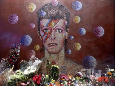 Floral tributes lie beneath a mural of British singer David Bowie, painted by Australian street artist James Cochran, aka Jimmy C, following the announcement of Bowie's death, in Brixton, south London, on January 11, 2016. British music icon David Bowie died of cancer at the age of 69, drawing an outpouring of tributes for the innovative star famed for groundbreaking hits like "Ziggy Stardust" and his theatrical shape-shifting style.