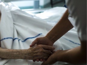 (FILES) A file picture taken on July 22, 2013 shows a nurse holding the hand of an elderly patient at the palliative care unit of the Argenteuil hospital, outside Paris. A panel set up at the request of President Francois Hollande on December 16, 2013 recommended legalising assisted suicide in France, where the debate on euthanasia has re-emerged after several end-of-life tragedies. The suicides of two elderly couples in November and the heartwrenching testimony of a politician who watched her terminally-ill mother die after taking pills have shocked and moved France, where euthanasia is illegal.AFP PHOTO / FRED DUFOURFRED DUFOUR/AFP/Getty Images ORG XMIT: POS1312161151512310 ORG XMIT: POS1504101413518393 // 1211 na euthanasia ORG XMIT: POS1511261852413923