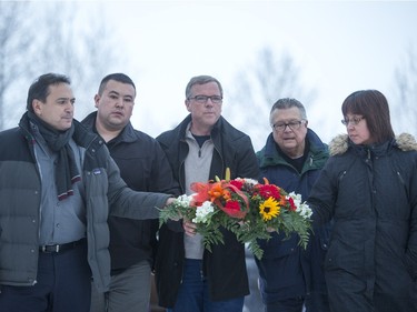 Federation of Saskatchewan Indian Nations Chief Perry Bellegarde, left, La Loche acting mayor Kevin Janvier, Premier Brad Wall, Public Safety Minister Ralph Goodale and Local MP Georgina Jolibois lay down flowers at a memorial at La Loche Community School on January 24, 2016.