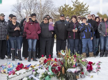 La Loche residents look on as Prime Minister Justin Trudeau (not pictured) lays flowers at a memorial at La Loche Community School on January 29, 2016.