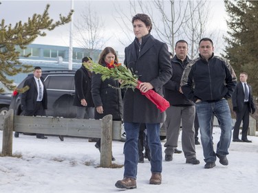 Prime Minister Justin Trudeau lays flowers at a memorial at La Loche Community School on January 29, 2016.