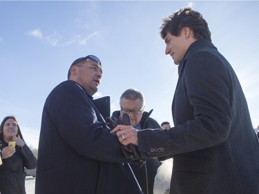 Prime Minister Justin Trudeau (R) speaks with Barry Poulegour while he is greeted by people from La Loche after arriving at the airport on January 29, 2016.