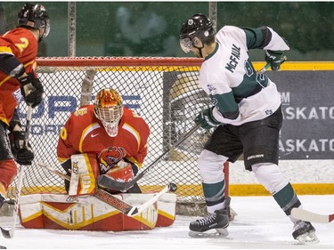 University of Saskatchewan defence Kendall McFaull tips a shot past University of Calgary Dinos goalie Steven Stanford in CIS men's hockey action, January 16, 2016.