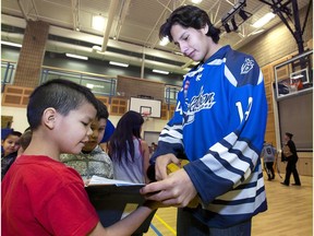 Saskatoon Blades' Dustin Perillat takes an interest in Kaden Mike-Dillon's scrap book of drawings while taking part in a ceremony at St. Mary's Wellness and Education Centre.