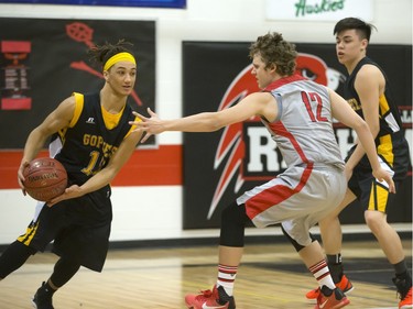 Isaac Collins of the Bedford Road Collegiate RedHawks (red colours) reaches out on defence to Marcel Arruda-Welch of the Garden City Fighting Gophers during opening game action in the annual BRIT basketball classic, January 7, 2016.