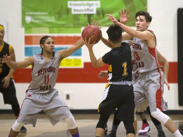 Justyn Lightle and Brett McMurtry of the Bedford Road Collegiate RedHawks (red colours) play defence against Christian De Leon of the Garden City Fighting Gophers during opening game action in the annual BRIT basketball classic, January 7, 2016.