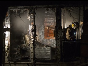A firefighter in the damaged remains of a house fire in the 1300 block of 8th Avenue North, January 13, 2016.