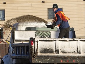 Kirk Morrow of All Seasons Landscaping shovels sand from the back of a truck on to a business parking lot at Avenue P and 22nd Street West to combat the wide spread ice problem, Nov. 19, 2015.