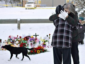 Residents console each other at the memorial near the La Loche Community School.