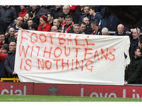 (FILES) This file photo taken on February 6, 2016 shows Liverpool fans holding a banner as they protest against the recently announced rise in ticket prices during the English Premier League football match between Liverpool and Sunderland at Anfield in Liverpool, north west England. Liverpool's owners on Wednesday apologised and scrapped controversial plans to hike Anfield ticket prices after 10,000 fans walked out of the ground in protest at the weekend.Principal owner John W Henry and chairman Tom Werner acted after legions of angry Reds fans stormed out of the ground in the 77th minute of Saturday's home game against Sunderland.  / AFP / LINDSEY PARNABYLINDSEY PARNABY/AFP/Getty Images