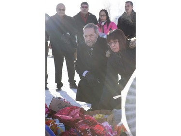 Local MP Georgina Jolibois (R) and NDP Leader Tom Mulcair lay flowers at a memorial at the La Loche Community High School on February 2, 2016.