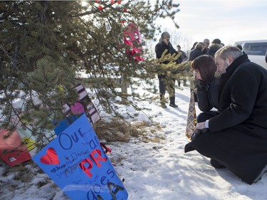 NDP Leader Tom Mulcair (L) and Local MP Georgina Jolibois look at some items and inscriptions after laying down flowers at a memorial at the La Loche Community High School on February 2, 2016.