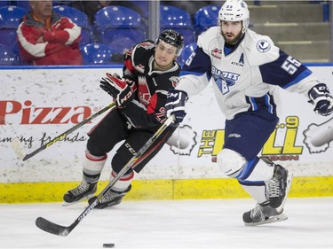 Saskatoon Blades' Colton Waltz moves the puck away from Moose Jaw Warriors' Noah Gregor in WHL action, February 28, 2016.