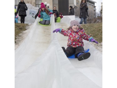Four-year-old Maggie Giroux (L) and seven-year-old Nevaeh Bitz slide down an ice slide at Frosted Gardens on the Bessborough Hotel grounds, February 6, 2016.