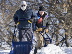 Derek Salomon, left, was on the roof of this Alexandra Ave. home helping out Chris Zbytobsky who was taking care of the home for a friend,  February 11, 2013. Chris says the melting and refreezing of the snow on the roof has left a 8 inch layer of ice at the eaves-troughs causing the melt water  to  seep into the home under the singles.