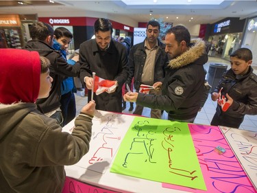 Mohammed Al-Helal (L) hands out Canadian flags before he and other newly arrived Syrian refugees handed out roses at Lawson Heights Mall in Saskatoon to thank Canadians, February 21, 2016.