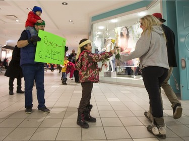 Newly arrived Syrian refugees hand out roses at Lawson Heights Mall in Saskatoon to thank Canadians, February 21, 2016.