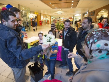 Syrian refugees distribute flowers and signs before they handed out roses at Lawson Heights Mall in Saskatoon to thank Canadians, February 21, 2016.