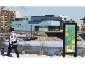 A pedestrian takes a walk on the trails across the river from the Remai Art Gallery