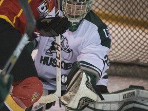 University of Saskatchewan Huskies goaltender Jordon Cooke scoops up a deflected puck from University of Calgary Dinos forward Coda Gordon on a Calgary power play in first period CIS Canada West playoff action from Rutherford Rink on campus in Saskatoon, February 26, 2016. (GordWaldner/Saskatoon StarPhoenix)