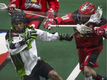 Jeremy Thompson of the Saskatchewan Rush, left, and Greg Harnett of the Calgary Roughnecks mix it up on the boards.