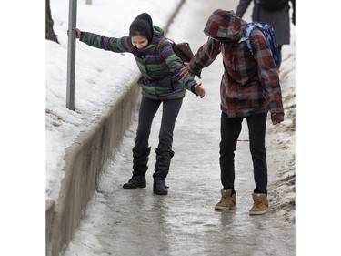 The freeze and thaw cycle has left city sidewalks very slippery, like this downhill slope on Wiggins Avenue near Elliott Street which students at the University of Saskatchewan must negotiate, February 9, 2016. Here Octavia McKay and Mafis Singer link up for balance.