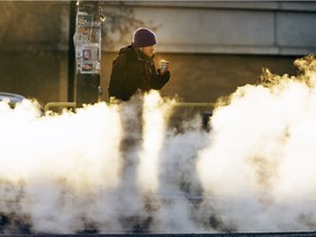 A pedestrian waits to cross Idylwyld Drive at 33rd Street with a hot beverage in the cold weather and exhaust fumes, Friday, February 12, 2016.