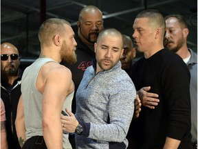 UFC featherweight champion Conor McGregor (left) and lightweight contender Nate Diaz (right) are held apart by UFC vice president of public relations Dave Sholler after a news conference at UFC Gym on Feb. 24, 2016